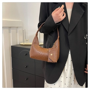 Detail view of woven leather texture on a brown hobo bag with a small coin pouch attachment