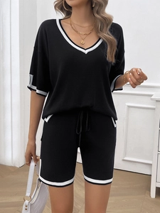 Detail of black V-neck casual set featuring white stripe trim and stylish knit texture