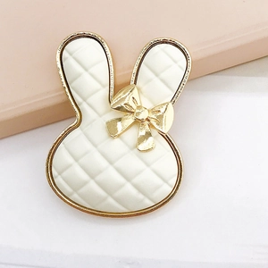 Detailed macro view of a white rabbit-shaped accessory with gold trim and plaid pattern