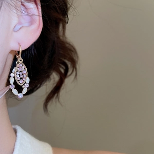 Close-up of elegant gold vintage earrings with pink rhinestones and white cat-eye stones