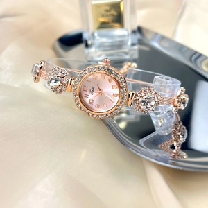 Close-up of elegant rose gold watch with pink dial and rhinestones on silk fabric