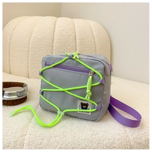Detail of trendy nylon crossbody bag with purple straps and neon green bungee cord accents