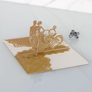 Detail of 3D gold glitter laser-cut Mr & Mrs wedding invite with couple silhouette
