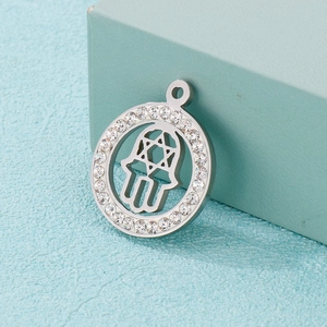 Macro shot of silver Hamsa Hand pendant with Star of David and sparkling zircon circle