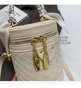Detail of woven leather bucket bag with gold padlock zippers and silk scarf handle