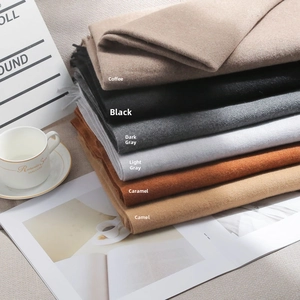 Folded pile of thick cashmere feel scarves in neutral colors for autumn and winter