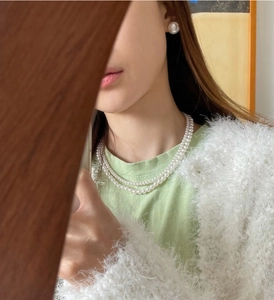Close-up of elegant double-layer white pearl necklace and matching stud earrings on model