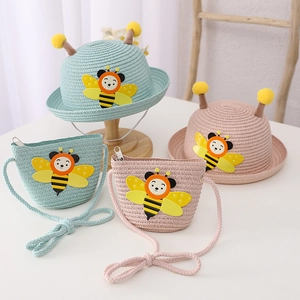 Close-up of children's woven straw sun hat and matching bag with 3D bee applique