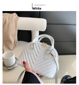 Close-up of white shell handbag with V-quilted texture and gold zippers for women
