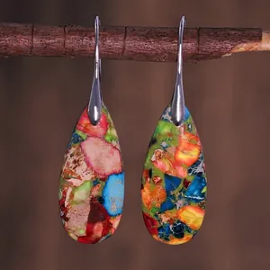 Detailed view of colorful teardrop stone earrings hanging on a natural wooden branch