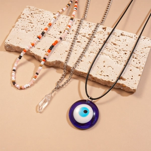 Detail of multi-layered necklace set featuring blue evil eye pendant and crystal beads