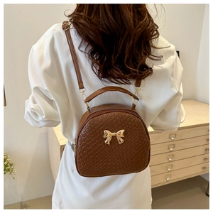 Dettaglio della borsa intrecciata marrone scuro con fiocco dorato indossata da una modella