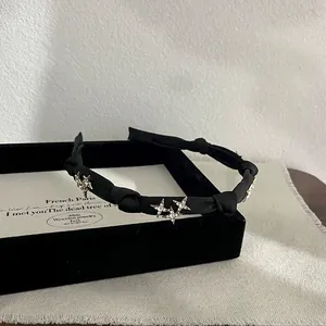 Detailed view of the black satin knotted headband with sparkling crystal star accents