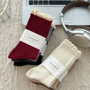 Lace trim knit socks in vintage wine red and grey stacked on a cozy woven blanket