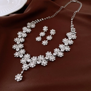 Dettaglio del set collana con fiori d'argento e orecchini lunghi su tessuto marrone
