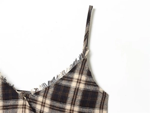 Close-up of brown plaid V-neck dress detail featuring fringe trim and soft fabric texture