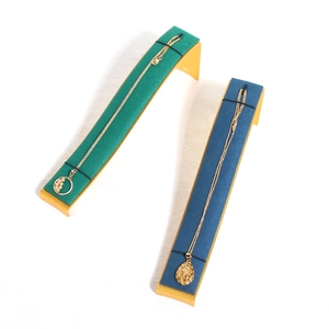 Curved microfiber jewelry display stand with green and blue velvet on gold metal base