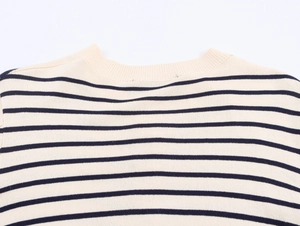 Gros plan détaillé d'un pull en maille rayé beige et bleu marine montrant le col rond