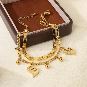 Detailed shot of double-layer gold heart bracelet featuring heart pendant and small beads