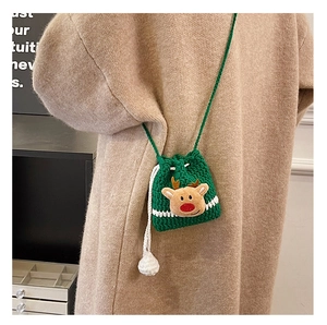 Detail of handmade green crochet reindeer bag with plush pom-poms on a wool coat