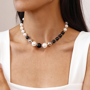 Close-up of elegant black and white faux pearl beaded necklace worn on a female model