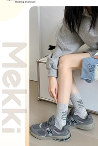 Close-up of knit mid-tube socks with heel lettering and heart print in light grey and blue