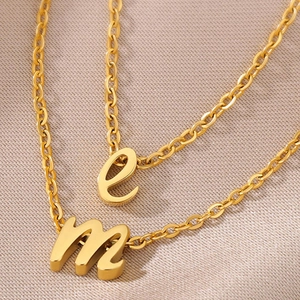 Detail der goldenen Anhänger mit Kleinbuchstaben e und m an einer klassischen O-Kette