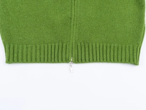 Dettaglio del cardigan in maglia verde erba con zip in metallo e bordo a coste