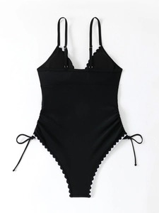 Detail of black one-piece swimsuit featuring white scallop edges and side drawstring details