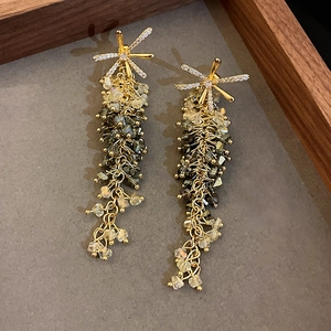 Macro view of crystal flower earrings with long gold tassels and starburst detailing