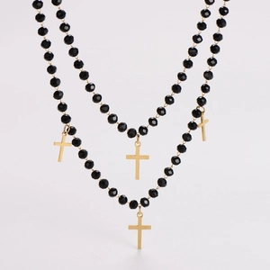 Close-up of double-layer beaded necklace with black faceted beads and gold crosses