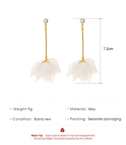 Macro detail of elegant long tassel flower earrings with crystal accents and gold finish