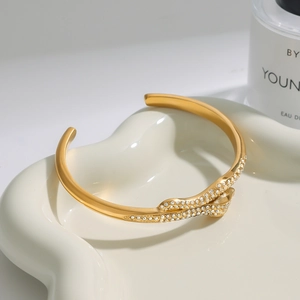 Macro detail of gold-plated snake-style open bangle with pave-set shimmering crystals