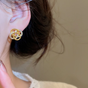 Détail des boucles d'oreilles nœud entrelacé doré avec zircons portées par un mannequin