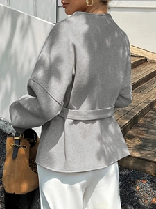 Detailed back view of a grey wool-like jacket featuring an elegant belted waist and ruffled hem