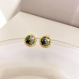 Detailed macro shot of vintage gold stud earrings with green crystals and small pearls