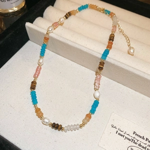 Détail d'un collier de perles d'eau douce colorées avec perles plaquées or sur plateau
