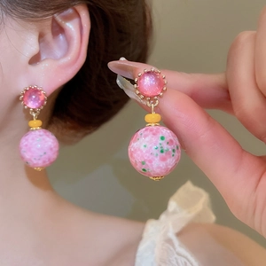 Close-up of pink resin drop earrings with marble texture on vintage gold mount