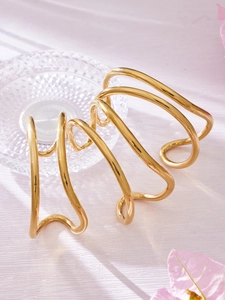 Dettaglio di un bracciale a polsino multistrato ondulato placcato oro 18k su petali rosa