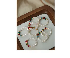 Detail of seven handmade baroque pearl and colorful beaded elastic rings on silk fabric