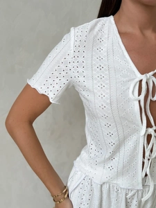 Detail of white cotton broderie anglaise short sleeve top with delicate ribbon ties