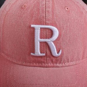 Macro d'une lettre R blanche brodée en 3D sur une casquette en coton sergé rouge délavé