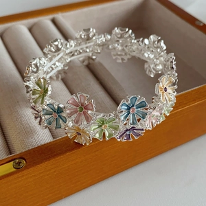 Macro detail of colorful enamel daisy charms on a silver metal elastic flower bracelet
