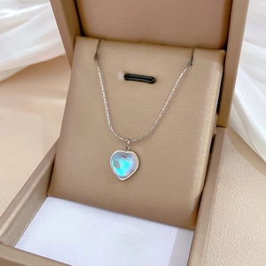 Macro shot of colorful heart pendant necklace in beige jewelry box on silk fabric