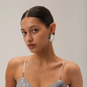 Close-up of model wearing silver polished round stud earrings with outer pavé glitter detail