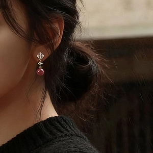 Close-up of red bead flower earrings with cubic zirconia on a female model's ear