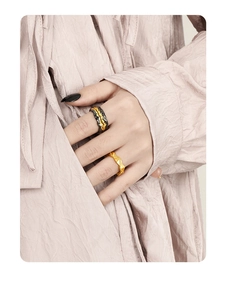 Close-up of irregular textured lava rings in gold and black-gold on a model's hand