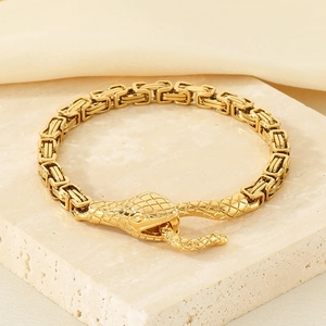 Macro shot of gold Byzantine chain bracelet with a detailed snake head clasp design