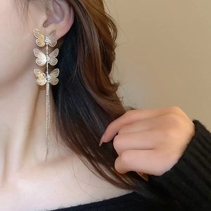 Detail view of gold butterfly tassel earrings with sparkling crystals worn by a model