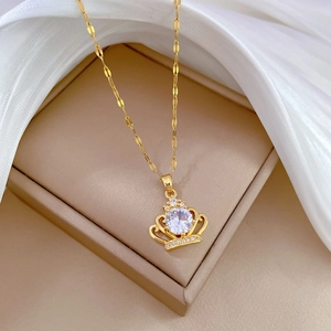 Elegant gold crown pendant necklace with round clear gemstone in a beige jewelry box